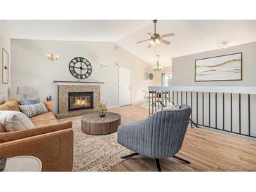 Cozy living room with a fireplace, vaulted ceiling, and modern decor, creating a warm and inviting space at 9712 Adams St, Thornton, CO 80229
