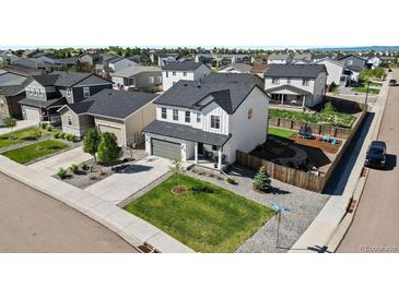 Beautifully landscaped two-story home with a spacious yard, gray roof, gray garage door and backyard fire pit at 140 Vista Cliff Cir, Castle Rock, CO 80104