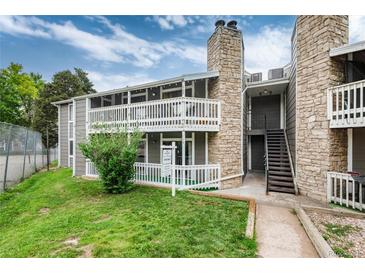 Condo exterior with gray siding, stone accents, and a well-maintained green lawn at 18103 E Kentucky Ave # 103, Aurora, CO 80017