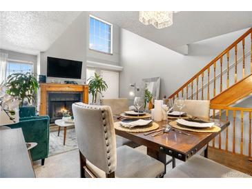 Open concept dining room featuring a fireplace, television, staircase, and large window for natural light at 5155 W 68Th Ave # 5, Westminster, CO 80030