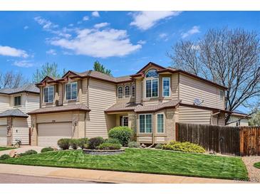 Charming two-story home with manicured lawn, mature landscaping, and neutral color palette at 7354 S Robb St, Littleton, CO 80127