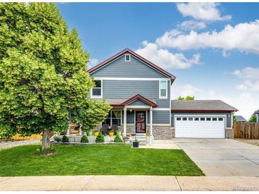 Charming two-story home with well-manicured lawn, attached garage, and covered front porch at 1824 Asoka St, Strasburg, CO 80136