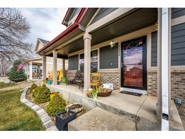 Inviting front porch with brick accents, potted plants, and a charming entrance to welcome you home at 1824 Asoka St, Strasburg, CO 80136