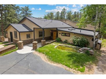 Stunning home with stone pillars, pond and lush landscaping, located on a beautiful large lot at 32173 Soda Creek Dr, Evergreen, CO 80439