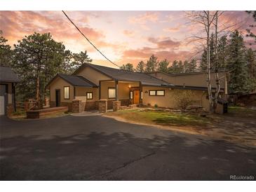 Charming home exterior with stone accents, covered entryway, and dark asphalt driveway at 32173 Soda Creek Dr, Evergreen, CO 80439
