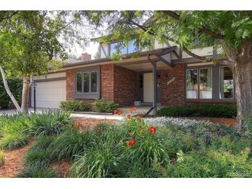 Charming brick home featuring well-maintained landscaping with vibrant flowers and a covered front entry at 12377 E Harvard Dr, Aurora, CO 80014