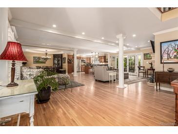 Spacious open-concept living room with hardwood floors, elegant columns, and seamless flow to kitchen and dining areas at 3720 S Willow Cir, Denver, CO 80237