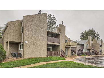 A multi-story apartment building with a textured exterior and wooden balconies and stairs is set in a green space at 5300 E Cherry Creek South Dr # 217, Denver, CO 80246