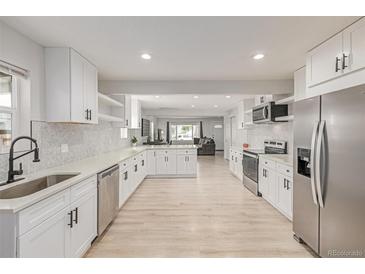 Spacious, renovated kitchen with stainless steel appliances, light wood floors, and white cabinets at 7752 Meade St, Westminster, CO 80030