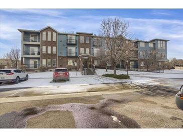 Three-story condo building with brick and blue siding, balconies, and snow-covered parking at 3601 E 103Rd Cir # B11, Thornton, CO 80229