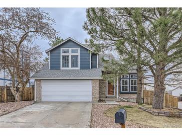 Charming home featuring blue siding, brick accents, an attached garage, and a well-maintained front yard at 9902 Independence St, Broomfield, CO 80021