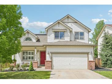 Charming two-story home with a red front door, a well-maintained lawn and a two car garage at 3745 Balderas St, Brighton, CO 80601
