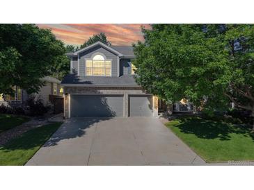 Charming two-story home featuring an attached three-car garage, attractive landscaping, and mature trees enhancing the property's appeal at 9845 Keenan St, Highlands Ranch, CO 80130