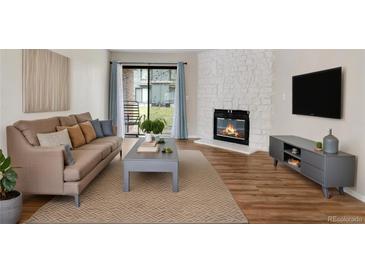 Comfortable living room boasts a modern fireplace, and decor plus sliding glass doors to the outside at 3656 S Depew St # 102, Denver, CO 80235