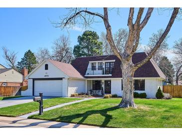 Beautifully landscaped front yard with healthy green grass and mature shade trees, showcasing home's exterior at 4970 S Chester St, Greenwood Village, CO 80111