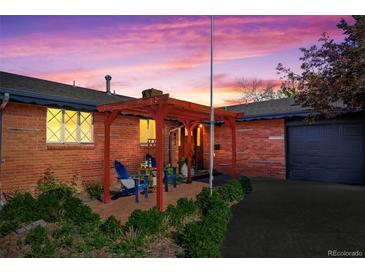 Charming brick home at dusk with a pergola-covered patio and well-maintained landscaping at 421 Iola St, Aurora, CO 80010