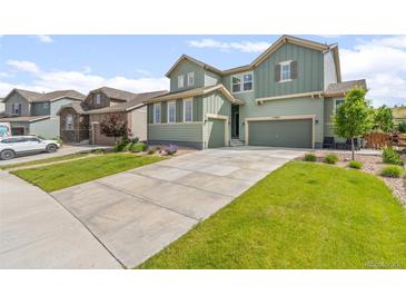 Beautiful home with a well-manicured lawn, a long driveway, and charming green siding at 17880 W 94Th Dr, Arvada, CO 80007