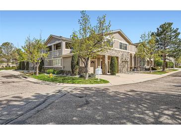 Beautiful exterior view of a tan two-story townhome with a stone facade and mature landscaping at 4222 S Blackhawk Cir # 6G, Aurora, CO 80014