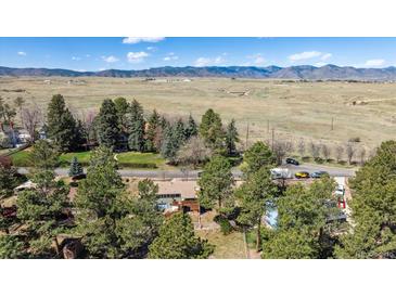 Expansive aerial shot showcasing the property, mature trees, and a backdrop of mountains in the distance at 7904 Hill Crest Dr, Louviers, CO 80131