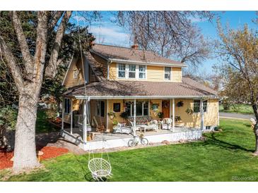 Charming yellow two-story home with a welcoming front porch, swing, and well-maintained lawn at 7835 Valley View St, Louviers, CO 80131