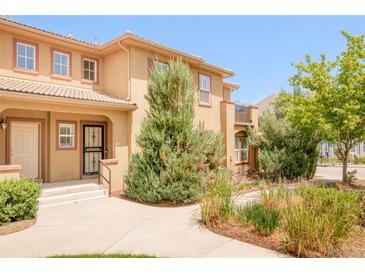Tan two-story townhome featuring a tile roof, neutral trim, private entrance and lovely landscaping at 7777 E 23Rd Ave # 1401, Denver, CO 80238