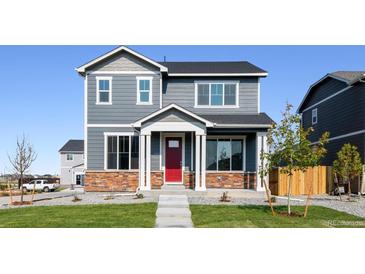 Charming two-story home featuring a red door and stone accents, set on a well-maintained lawn at 28621 E 8Th St, Watkins, CO 80137