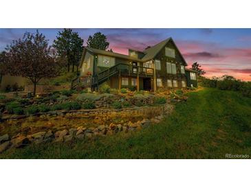 Stunning multi-level home featuring a beautifully landscaped yard with a charming water feature at twilight at 1549 Hillside Cir, Sedalia, CO 80135