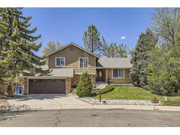Charming two-story home featuring stone accents, a well-manicured lawn, and mature trees at 1973 S Pitkin St, Aurora, CO 80013