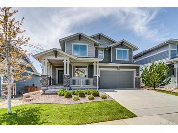Charming two-story home featuring a covered porch, manicured lawn, and attached two car garage at 16978 W 87Th Ave, Arvada, CO 80007