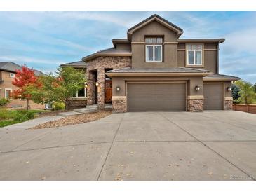 Stunning two-story home with stone accents, three-car garage, and beautiful landscaping at 14022 E Fair Pl, Centennial, CO 80111