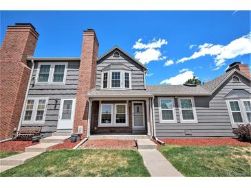 Charming gray townhome with red brick chimney, green lawn, and blue sky at 16901 E Chenango Ave # E, Aurora, CO 80015