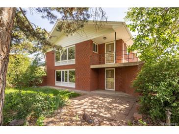 Charming red brick home featuring a unique balcony and mature landscaping at 7475 W Vassar Ave, Lakewood, CO 80227