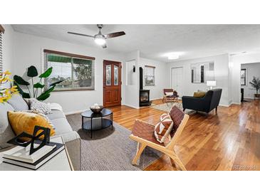 Inviting living room with hardwood floors, ceiling fan, wood burning stove, and lots of natural light at 8881 Lilly Dr, Thornton, CO 80229