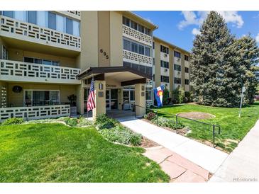 Inviting condo building showcasing professional landscaping, flags, and a covered entryway at 695 S Alton Way # 5A, Denver, CO 80247