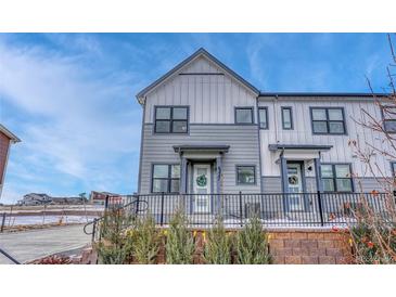 Modern two-story townhome with gray and white exterior, landscaped yard, and black metal fence at 9275 Merino Ct # A, Littleton, CO 80125