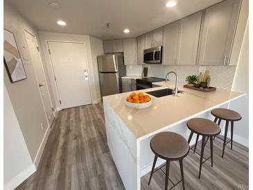 Modern kitchen featuring gray cabinetry, stainless steel appliances, and quartz countertops with seating at 100 Park Ave # 1405, Denver, CO 80205