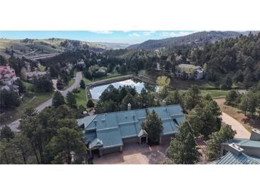 Stunning aerial view of a home with a blue roof, private pond, and lush mountain scenery at 867 Hill And Dale Rd # B, Golden, CO 80401