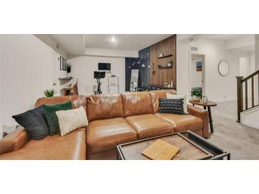 Finished basement with a large, comfortable leather couch and space for a home gym at 6619 Mariposa Ct, Denver, CO 80221