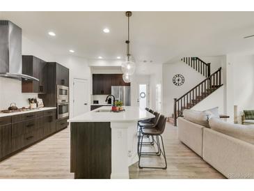 Bright, open kitchen features a large island with seating, stainless steel appliances and modern finishes at 6619 Mariposa Ct, Denver, CO 80221