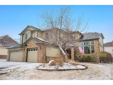 Two-story home with brick and siding exterior, a three-car garage, and an American flag on display at 13516 Thorncreek Cir, Thornton, CO 80241