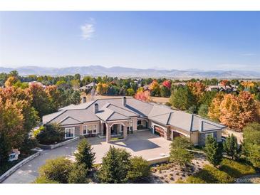 Expansive home with large driveway and meticulously landscaped front yard, against a backdrop of mountains and colorful foliage at 8833 Portico Ln, Longmont, CO 80503