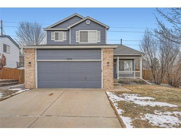 Two-story home with a blue exterior, brick accents, a two-car garage, and a well-maintained front yard at 22162 E Alamo Ln, Centennial, CO 80015