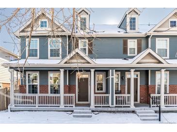 Two-story townhome with gray siding, brick accents, and a front porch at 14721 E Poundstone Dr, Aurora, CO 80015