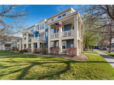 Inviting two-story townhome featuring a charming blue exterior and a welcoming front porch with an American flag at 9478 E 108Th Ave, Commerce City, CO 80640