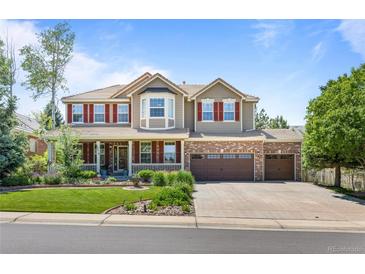 Inviting two-story home featuring a covered front porch, manicured lawn, and a three-car garage at 19616 E Pinewood Dr, Aurora, CO 80016