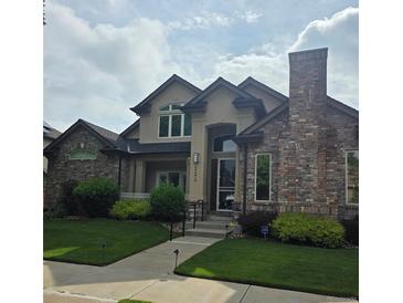 Charming two-story home features a brick chimney, manicured lawn, and inviting front entrance at 222 S Olive St, Denver, CO 80230