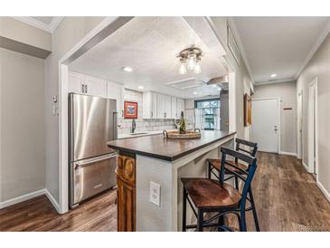 Modern kitchen features stainless steel appliances, white cabinets, and a breakfast bar with seating at 7250 Eastmoor Dr # 119, Denver, CO 80237
