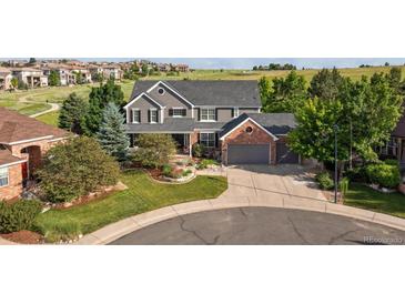 Charming two-story home featuring a landscaped yard, covered porch, and attached two-car garage with brick accents at 10660 Weathersfield Ct, Highlands Ranch, CO 80129