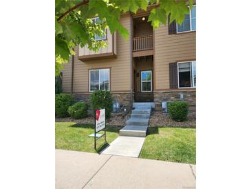 Inviting two-story townhome with a private balcony, stone accents, and manicured lawn at 1211 Bistre St, Longmont, CO 80501