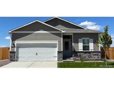 Charming single-Gathering home featuring a two-car garage, stone accents, and manicured lawn at 2225 Alyssa St, Fort Lupton, CO 80621